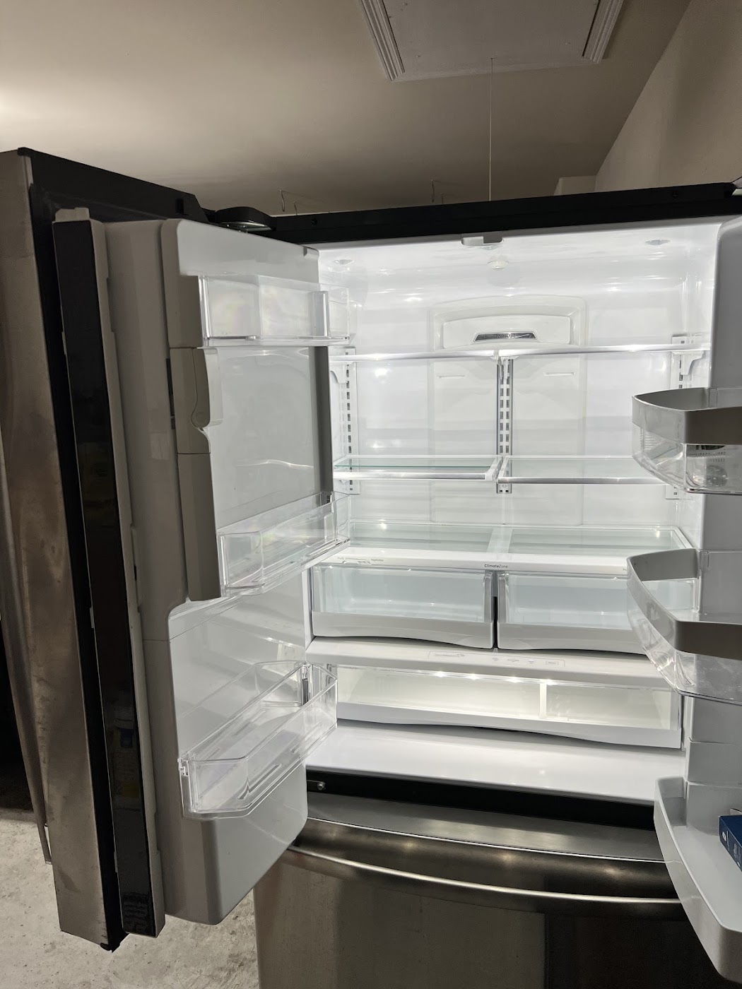 Emptied stainless French-door refrigerator with the doors open